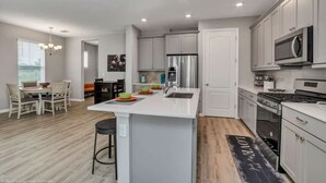 A modern kitchen with white cabinetry, stainless steel appliances, and a central island.