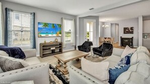 A living room with a sofa, armchairs, a coffee table, and a painting of a beach scene.