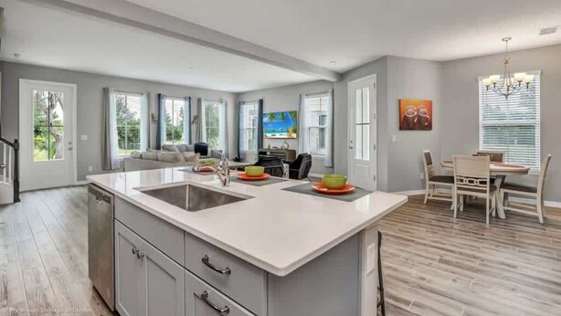 A spacious kitchen with a large island, a dining area with a table and chairs, and a view of the outdoors through large windows.