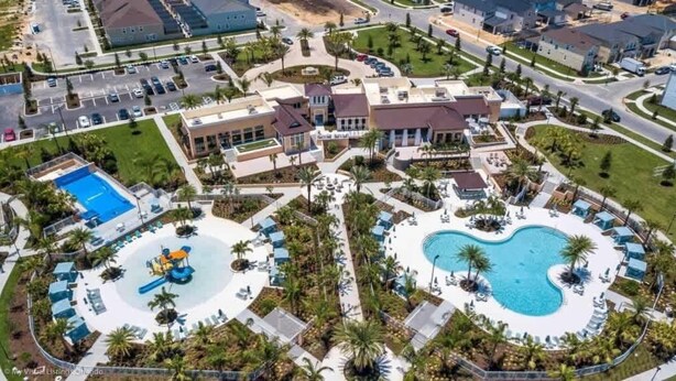 Luchtbeeld van een resort met meerdere zwembaden, palmbomen en een centraal gelegen waterpark.