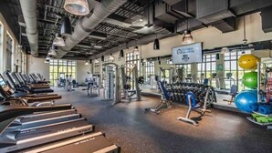 Een sportschool met loopbanden, krachtapparaten en fitnessballen.