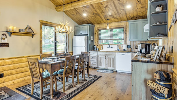 A rustic kitchen with wooden beams, a chandelier, and a 'Welcome' bear decoration. - Quiet Lakefront Conover Cabin Near ATV Trails (Conover)