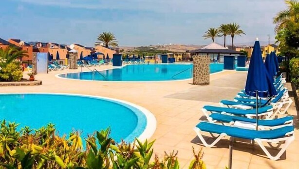 A resort pool area with multiple swimming pools, lounge chairs, and umbrellas. - Lemon Terraced House (Playa del Inglés)