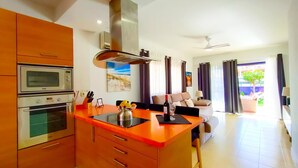 A modern kitchen with a central island, built-in oven, microwave, and a stainless steel range hood. - Lemon Terraced House (Playa del Inglés)