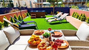 A rooftop terrace with a dining table set for breakfast, surrounded by lounge chairs and a small garden area. - Lemon Terraced House (Playa del Inglés)