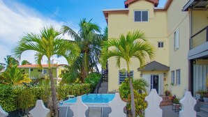 Un edificio residenziale con piscina, palme e una scala che conduce all'ingresso.