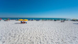A sandy beach with umbrellas and beach chairs.