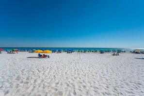 Ein Sandstrand mit Sonnenschirmen und Liegestühlen.