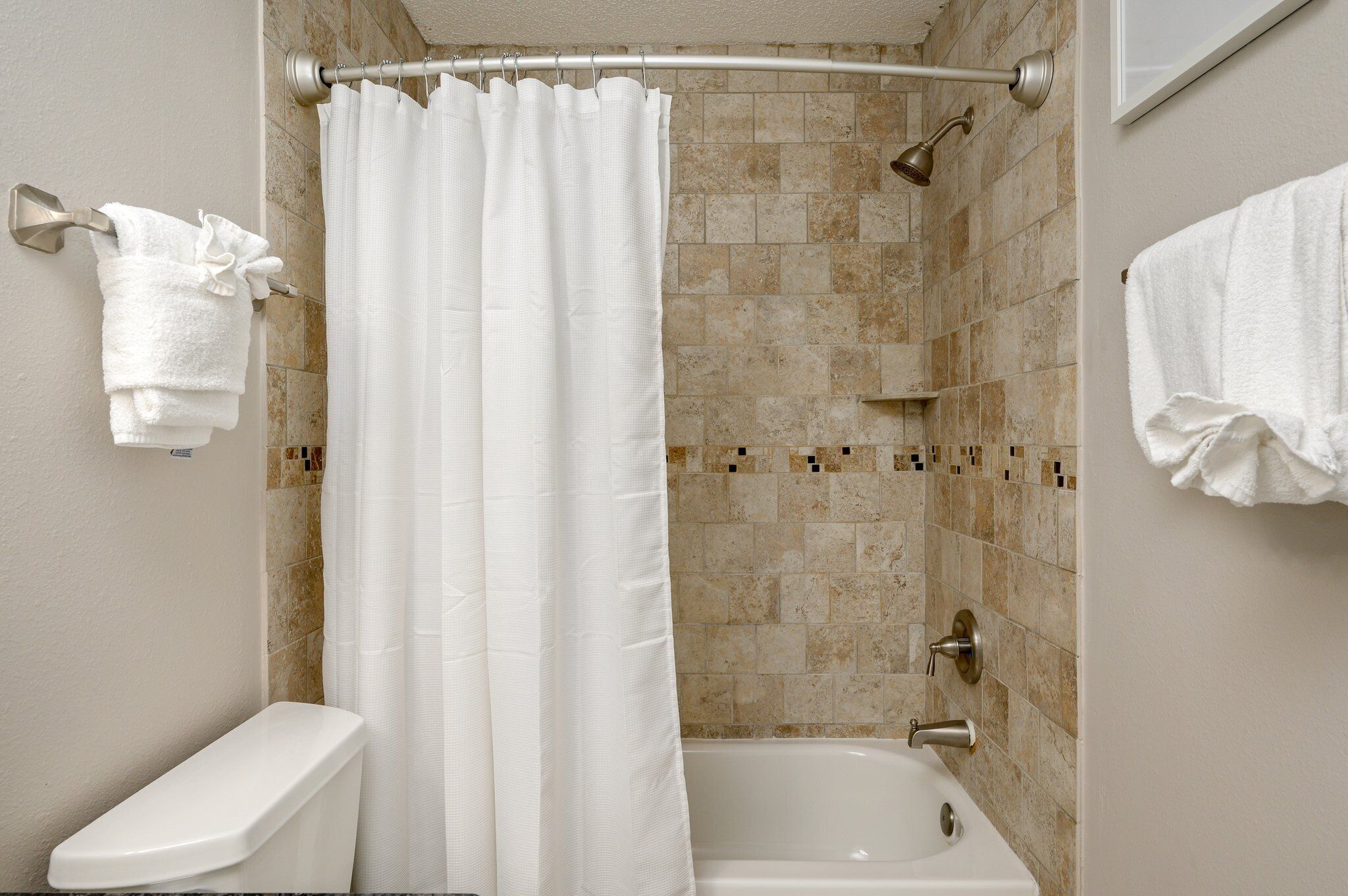Une salle de bain avec un rideau de douche, une baignoire et des toilettes.