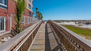 A wooden boardwalk leading to a beach with a red building on the left. - 200 yards to private gated beach access! 3BR/2BA. Quiet location in Destin (Destin)