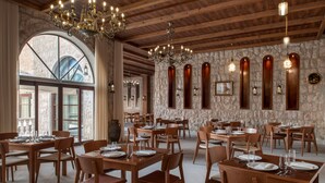 Un restaurant avec des tables et des chaises en bois, des murs en pierre et des lustres.
