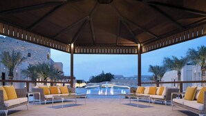 Un espace extérieur aménagé avec des canapés et des tables confortables, une fontaine et une vue sur un bâtiment historique et un pont.
