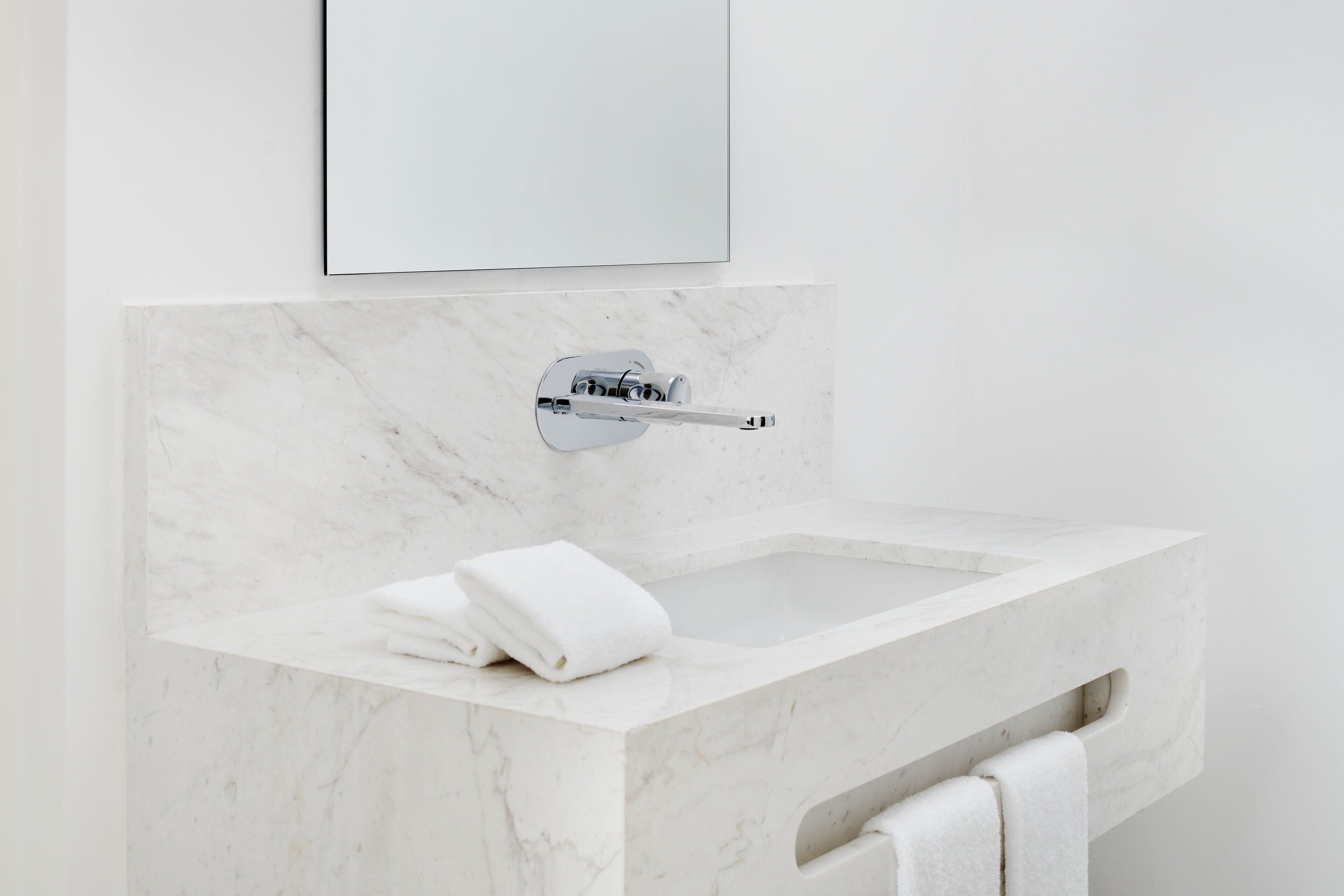 A bathroom with a marble sink, a towel rack, and a mirror.