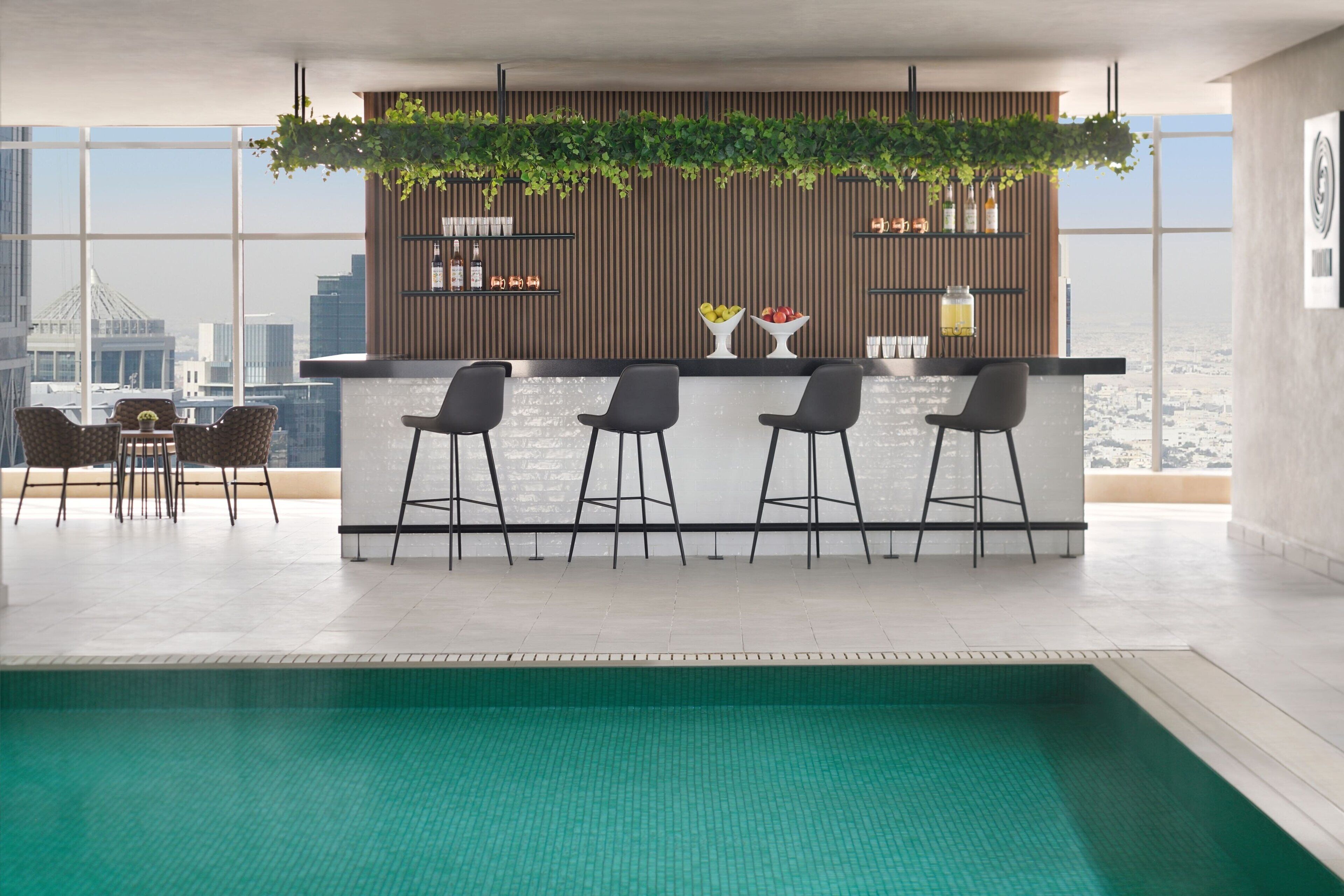 A modern bar area with a pool, bar stools, and a city view.