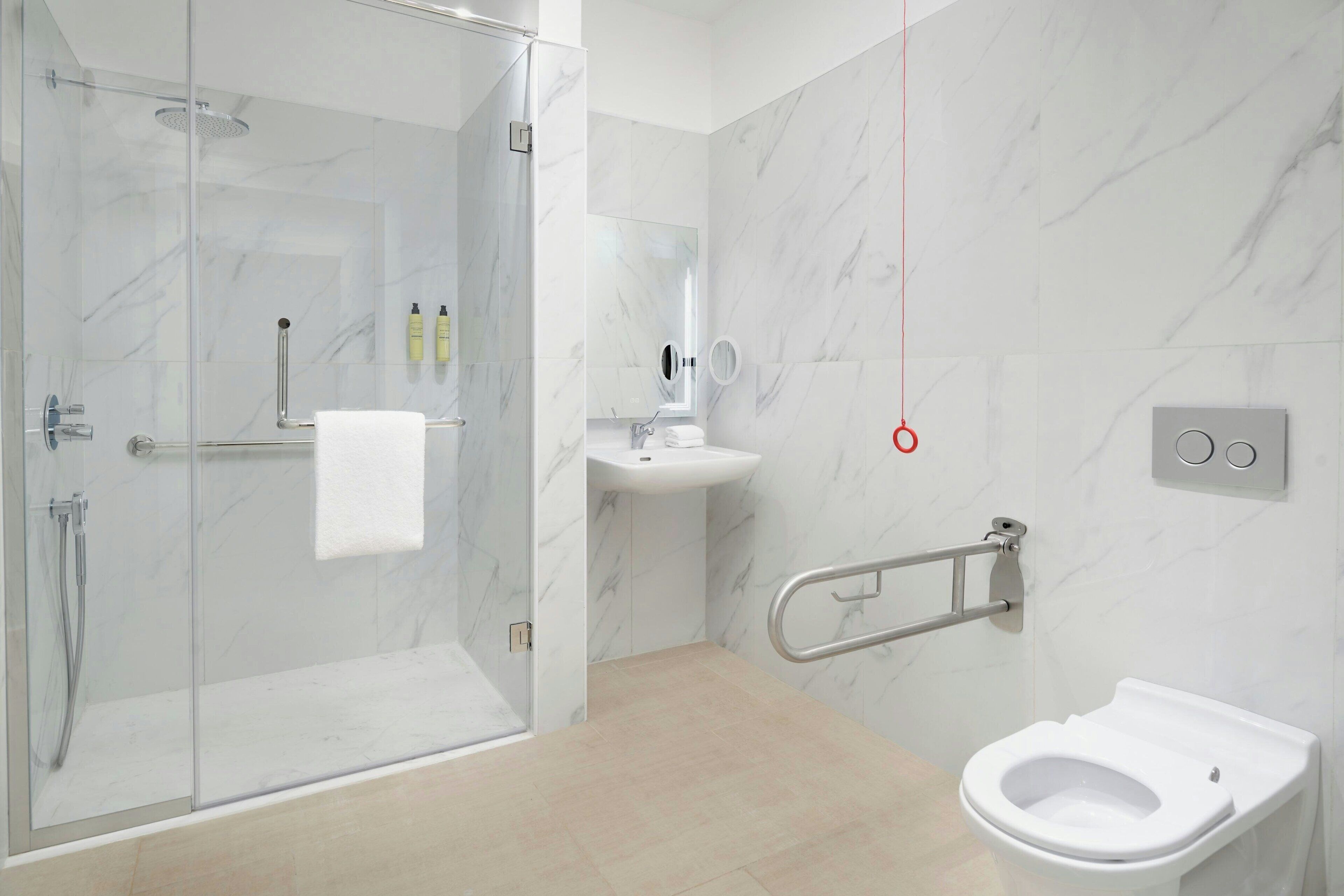 A modern bathroom with a glass shower enclosure, a white sink, and a toilet.