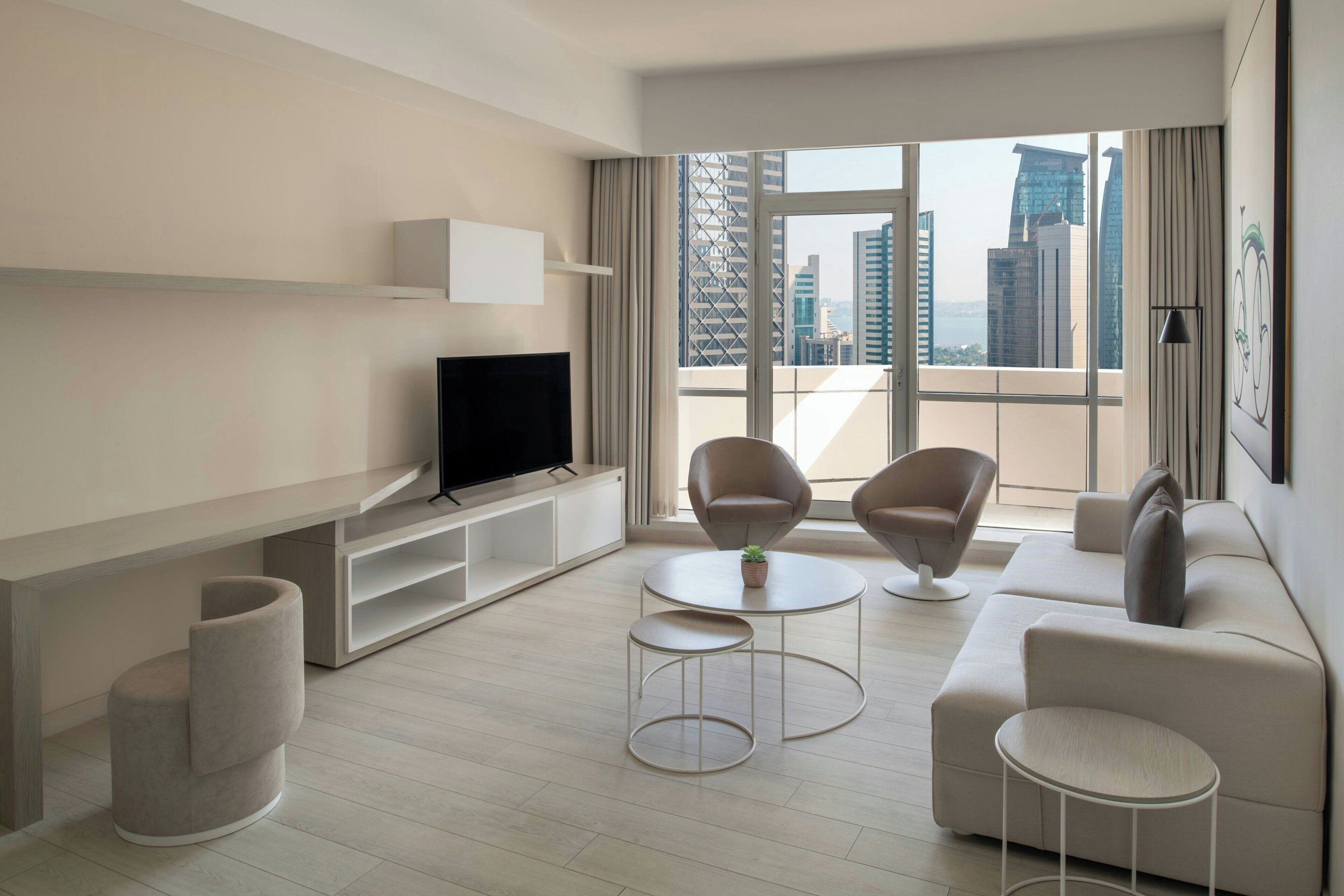 Una sala moderna con un televisor de pantalla plana, dos sillones, un sofá y una mesita de centro.