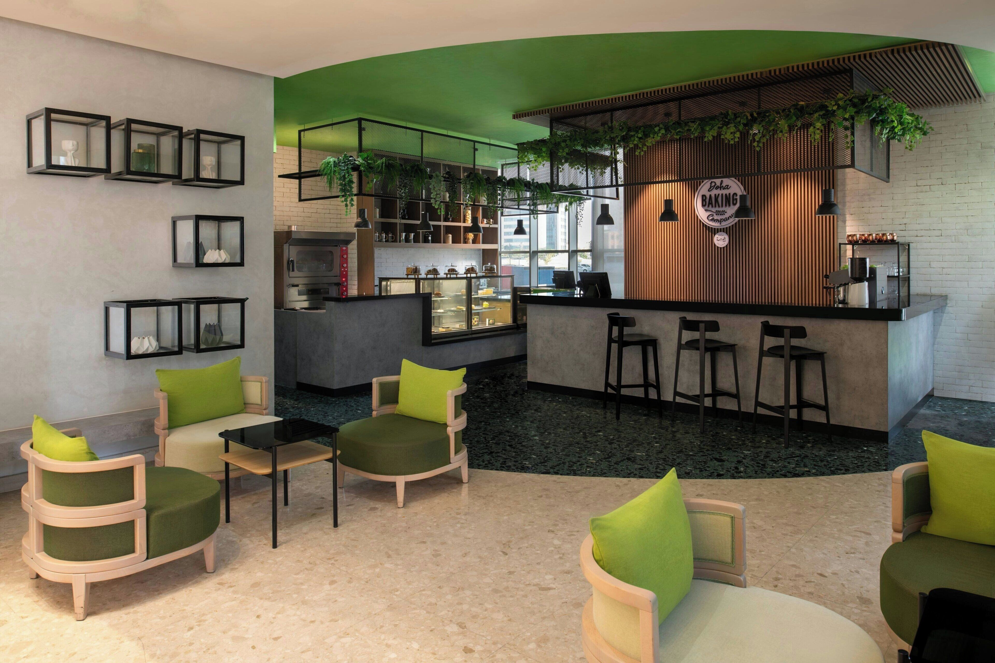 Un interior moderno con una zona de bar, asientos con cojines verdes y un techo verde.