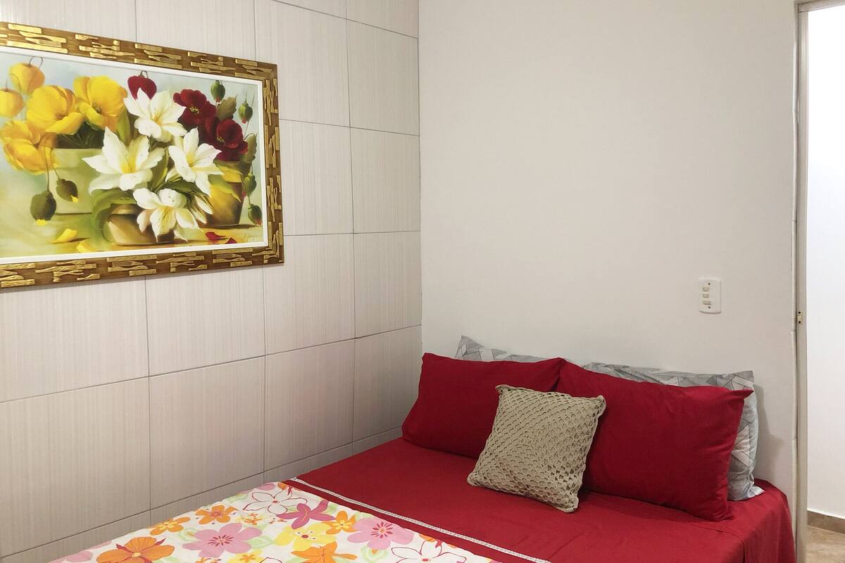 Um quarto com uma cama, um quadro na parede e uma porta.