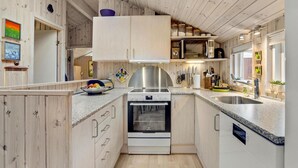 Een compacte keuken met houten wanden, een inbouwoven, een magnetron en een roestvrijstalen afzuigkap.