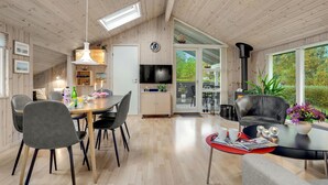 Een gezellig interieur van een chalet met een eethoek, keuken en een groot raam met uitzicht op de natuur.