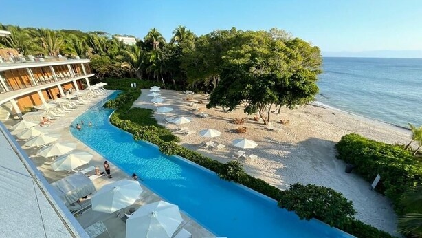 Un complexe hôtelier doté d’une piscine, d’une plage et de chaises longues.