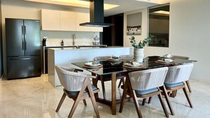Une cuisine moderne dotée d’un îlot central, d’appareils électroménagers noirs et d’un coin repas comprenant six chaises et une table en verre.