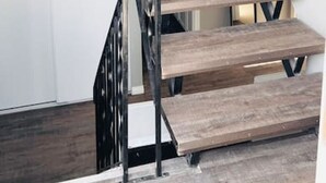 A staircase with wooden steps and black metal railings leading to a kitchen area. - Spacious 2-bedroom apartment (Camrose)