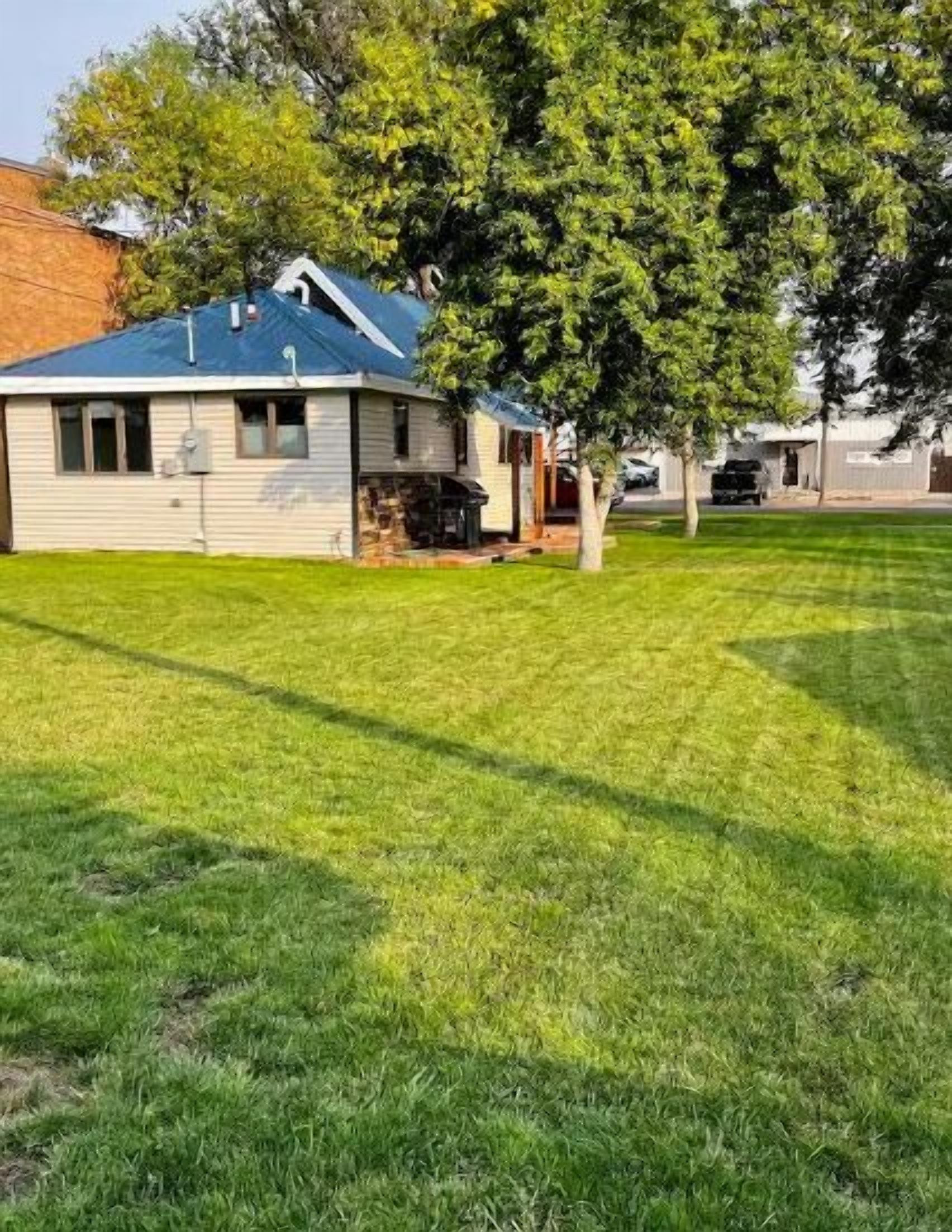 Une maison de plain-pied avec un toit bleu, un petit garage attenant et une pelouse bien entretenue.