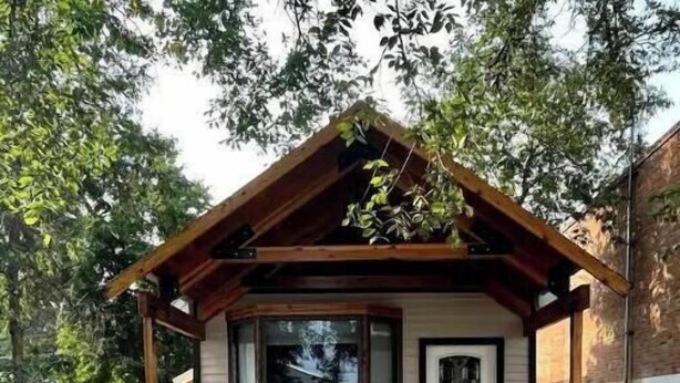 Una casa con un portico coperto, gradini in pietra e una porta con una finestra sopra.