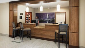 A reception area with a wooden reception desk, bar stools, a bookshelf, and a large window with a view of a bridge. - 1 Bedroom | Free Wi-Fi, Pool, Free Breakfast (Durham)