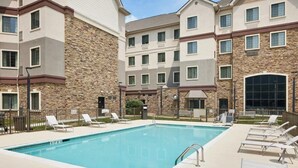A swimming pool with lounge chairs and a stone building in the background. - 1 Bedroom | Free Wi-Fi, Pool, Free Breakfast (Durham)