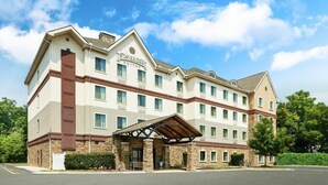 A multi-story hotel with a covered entrance, multiple windows, and a stone facade. - 1 Bedroom | Free Wi-Fi, Pool, Free Breakfast (Durham)
