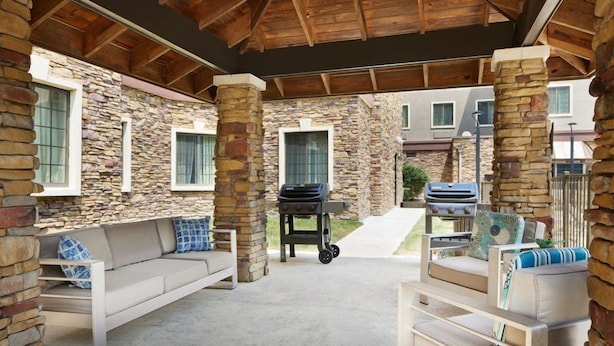 An outdoor patio with stone walls, a barbecue grill, and seating areas. - 1 Bedroom | Free Wi-Fi, Pool, Free Breakfast (Durham)