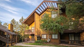 Ein mehrstöckiges Gebäude mit Holzfassade, einem Balkon und einer überdachten Außenbereich.