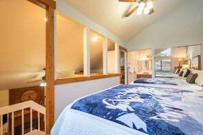 Een slaapkamer met een groot bed, een houten hoofdbord, een plafondventilator en uitzicht buiten door een raam.