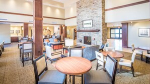 A spacious lobby with a fireplace, multiple seating areas, and a reception desk. - Accessible 1-Bedroom Suite, Roll-In Shower (Folsom)