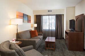Une chambre d’hôtel avec un canapé, une petite table, une télévision et un meuble.