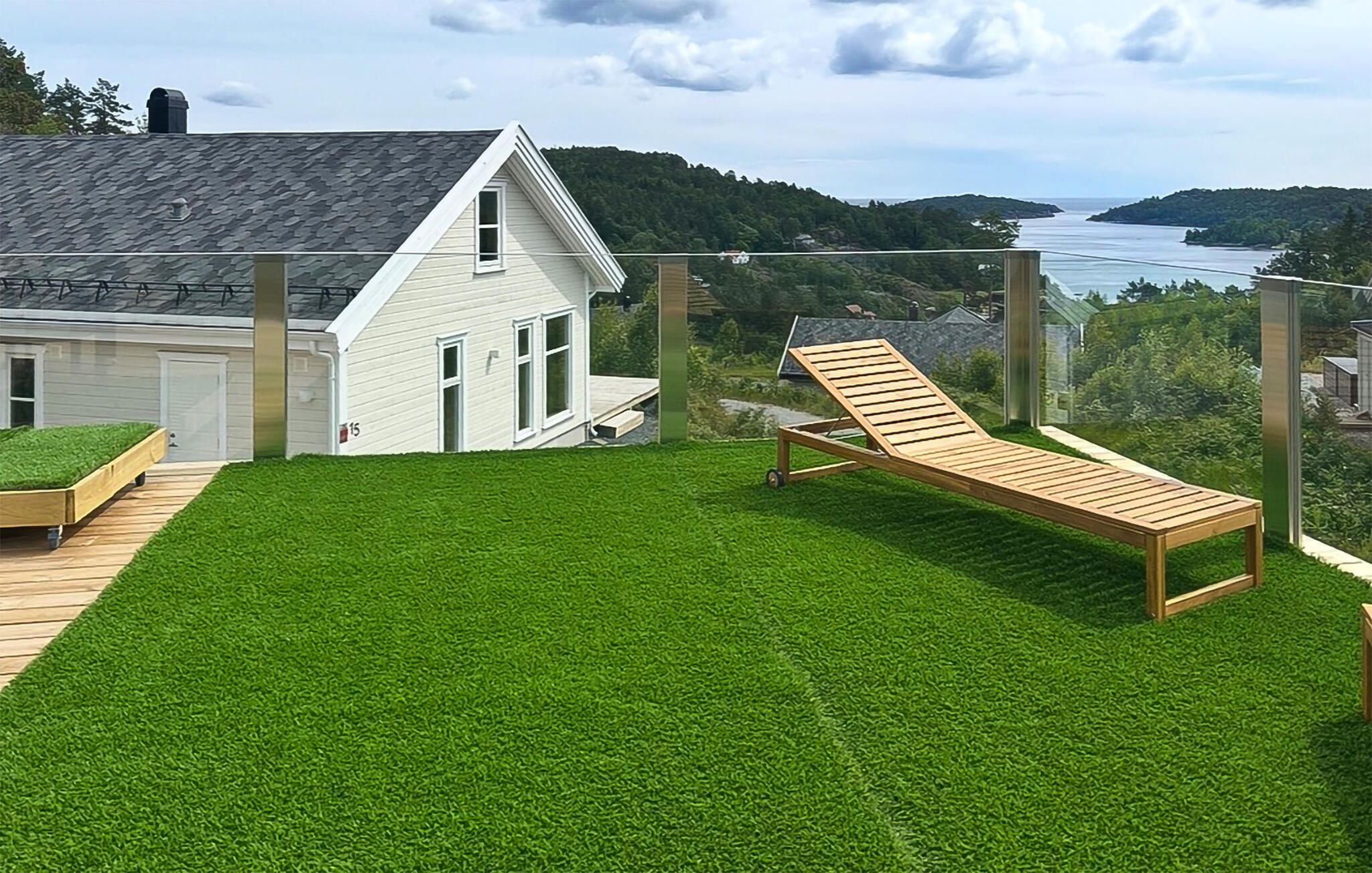 A house with a white exterior, a wooden deck, and a lawn.