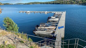 En brygga med flera båtar förtöjda, en trappa som leder ner till vattnet och en fri utsikt över det omgivande landskapet.