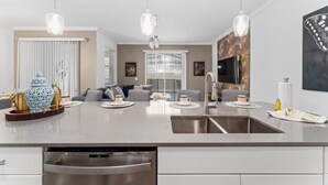 A modern kitchen with a central island, stainless steel appliances, and pendant lighting.