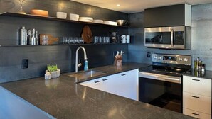 A modern kitchen with a dark countertop, stainless steel appliances, and a built-in oven. - Flawless One Bedroom Old Town Scottsdale Condo (Scottsdale)