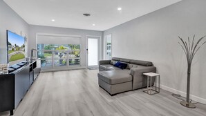 A modern living room with a grey sofa, a small side table, and a TV on a black stand.