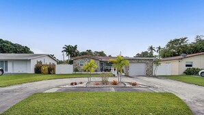 A residential area with two houses, a driveway, and a well-maintained lawn.