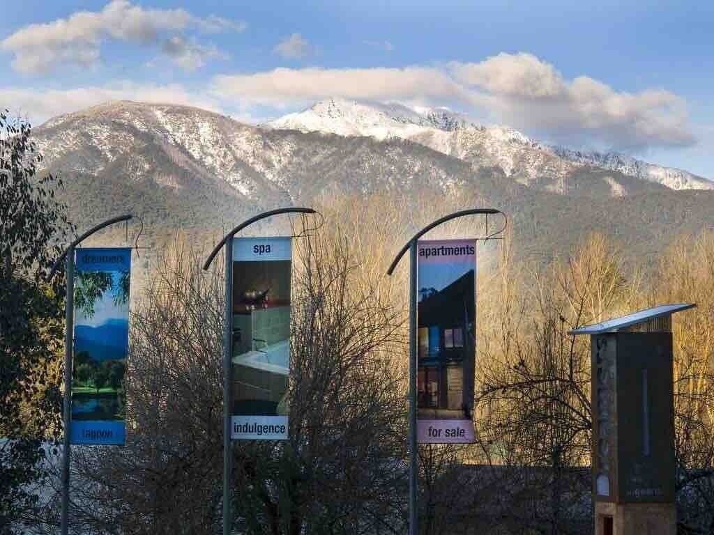 Un paysage de montagne avec des panneaux indiquant « Dreamers », « Spa », « Bien-être » et « Appartements à vendre ».
