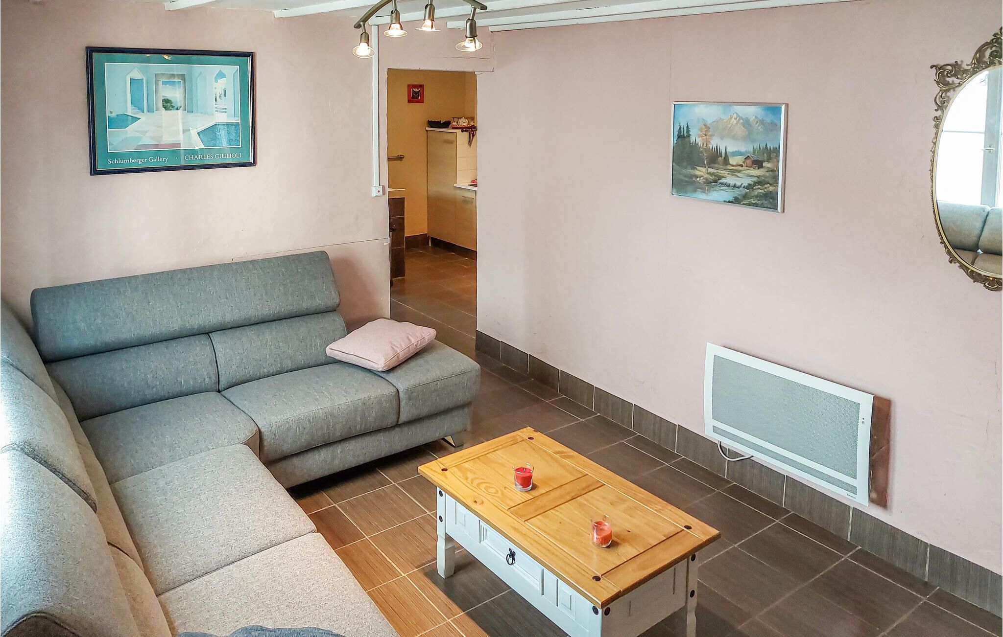 A living room with a grey sofa, a wooden coffee table, a TV, and artwork on the walls.