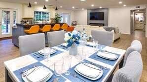 A modern kitchen with a central island, bright orange chairs, and a dining area set for six with a blue tablecloth and white plates. - Spacious Scottsdale home with resort yard, heated pool included in price! (Scottsdale)