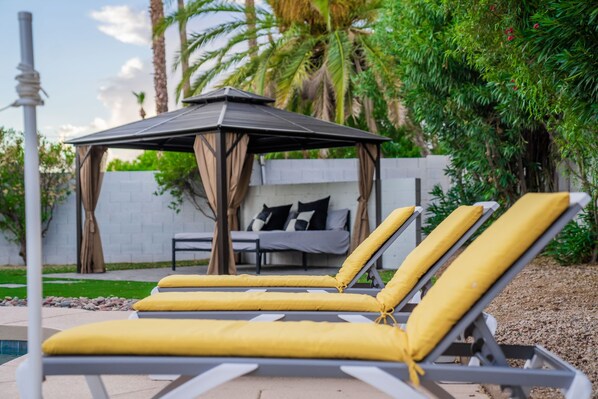 A poolside area with lounge chairs and a gazebo.