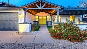 A house with a garage, a covered porch, and a well-maintained garden. - Spacious Scottsdale home with resort yard, heated pool included in price! (Scottsdale)