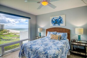 Relax in this serene hotel room with a large bed, ceiling fan, and stunning ocean views.