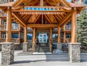 Enter a mountain lodge-style retreat with a prominent entrance featuring a canopy and stone pillars.